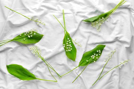 Beautiful lily-of-the-valley flowers on light fabric background