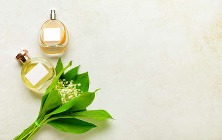 Bottles of perfume and lily-of-the-valley flowers on light background