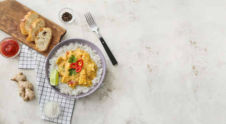 Bowl of tasty chicken curry with rice and ingredients on light backgroundの写真素材