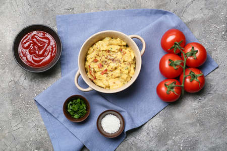 Pot of tasty chicken curry and ingredients on grunge background