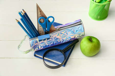 Pencil case with stationery on wooden background
