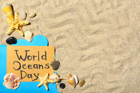 Paper sheet with text WORLD OCEAN DAY and sea shells on sandの写真素材