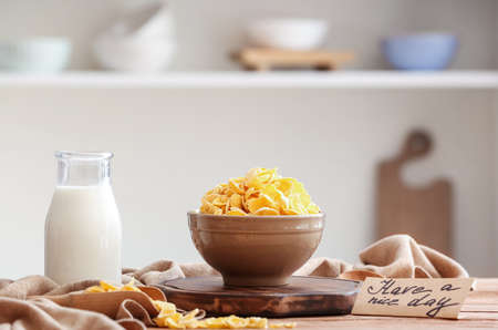 Bowl with delicious cornflakes, bottle of milk and card with text HAVE A NICE DAY on wooden tableの写真素材