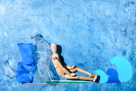 Mannequin with garbage and paper sea waves on color background. Ecology concept