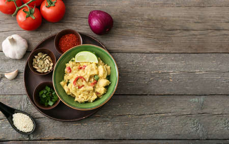 Bowl of tasty chicken curry and ingredients on wooden backgroundの写真素材