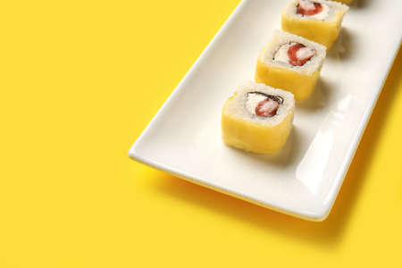 Plate with delicious sushi rolls on color background, closeup