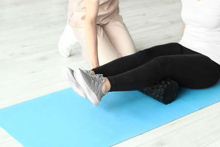 Mature woman training with physiotherapist on mat in rehabilitation center