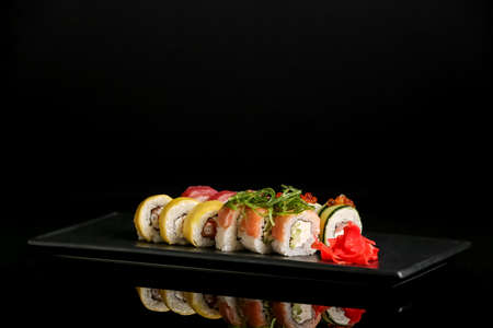 Tray with tasty sushi rolls, chuka and ginger on dark backgroundの写真素材