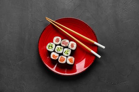 Plate with delicious maki rolls and wooden chopsticks on dark backgroundの写真素材