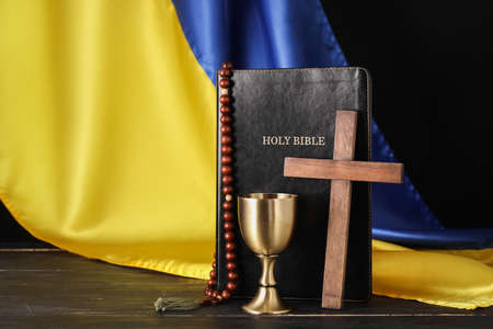 Holy Bible with rosary beads, cross, chalice and flag of Ukraine on dark wooden backgroundの写真素材