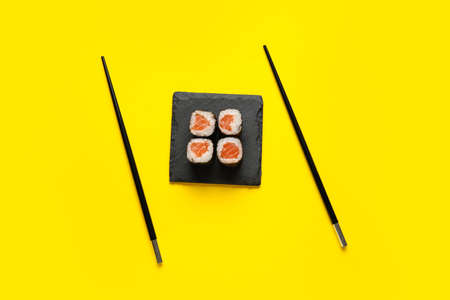 Board with delicious salmon maki rolls and chopsticks on color backgroundの写真素材