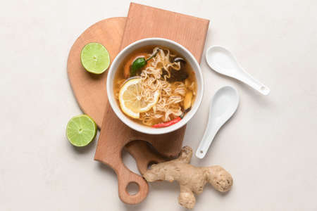 Bowl of spicy Thai soup on light background