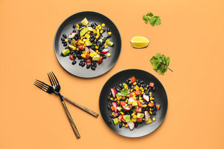 Plates of tasty Mexican vegetable salad with black beans and radish on color backgroundの写真素材
