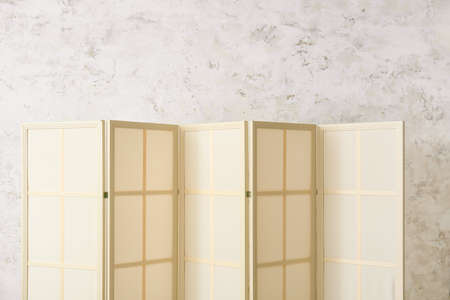 Beige folding screen near light wallの写真素材