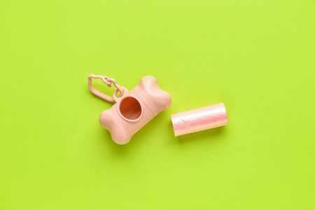 Dispenser with pet waste bags on color background