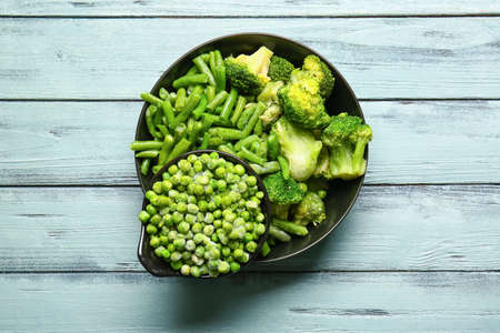 Bowl with frozen green vegetables on wooden backgroundの写真素材