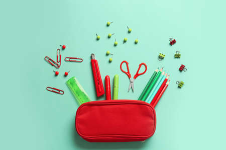 Pencil case and stationery on color background