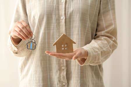 Woman holding figure of house and key with keychain, closeupの写真素材