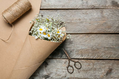 Bouquet of beautiful chamomile flowers, scissors and rope on wooden backgroundの写真素材