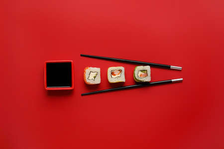 Delicious sushi rolls, chopsticks and bowl with soy sauce on color backgroundの写真素材