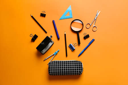 Pencil case with stationery on color background