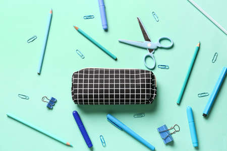 Pencil case with stationery on color background