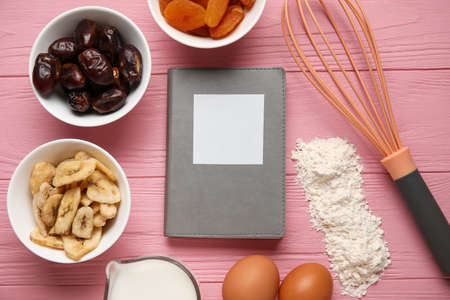 Recipe book, different ingredients and whiskey on color wooden background