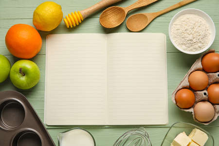 Opened recipe book and different ingredients on color wooden backgroundの写真素材