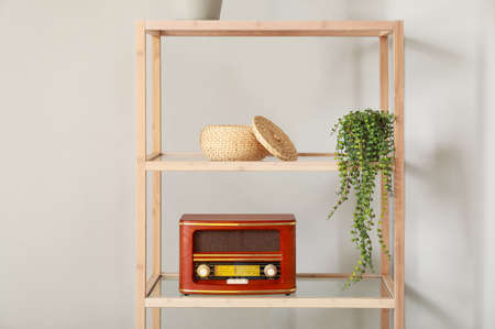 Wooden bookcase with retro radio receiver near light wallの写真素材
