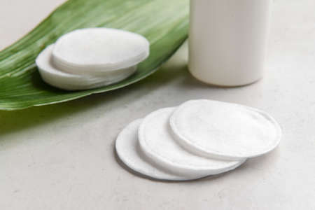 Clean cotton pads and palm leaf on light table, closeup