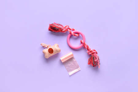 Dispenser, pet waste bags and toy on lilac background