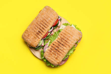 Board with tasty ciabatta sandwiches on color backgroundの写真素材
