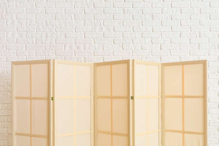 Stylish folding screen near brick wallの写真素材