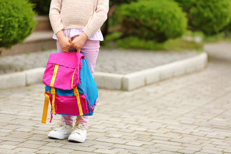 Little school girl with backpack outdoors
