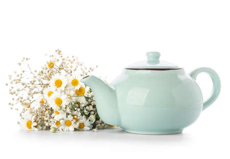Teapot of tasty tea and chamomile flowers on white backgroundの写真素材
