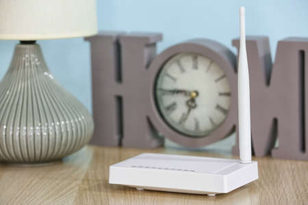 Modern wifi router on table near blue wall