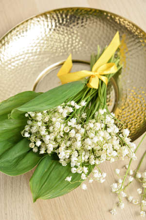 Plate with beautiful lily-of-the-valley flowers on table, closeup