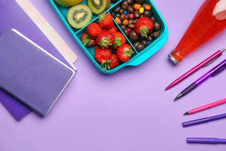 Lunchbox with tasty food and stationery on color backgroundの写真素材