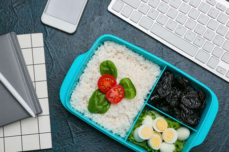 Lunchbox with tasty food, stationery and keyboard on color backgroundの写真素材