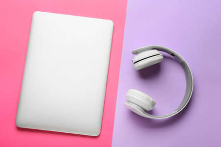 Modern laptop and headphones on color background