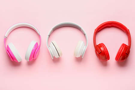 Different modern headphones on pink background