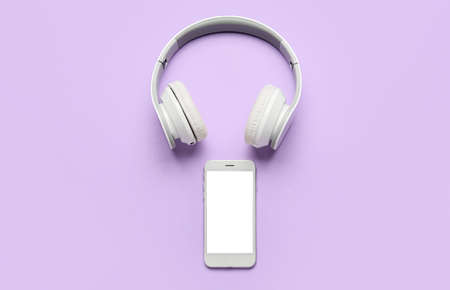 Modern headphones and mobile phone on color backgroundの写真素材