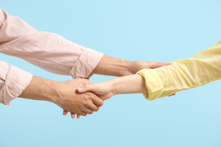 Man shaking woman's hand on blue background