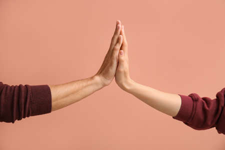 Woman and man giving each other high-five on beige backgroundの写真素材