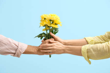 Man giving flowers to woman on blue background