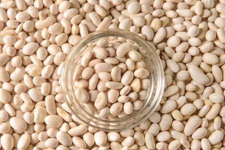 Glass bowl on raw beans, closeup