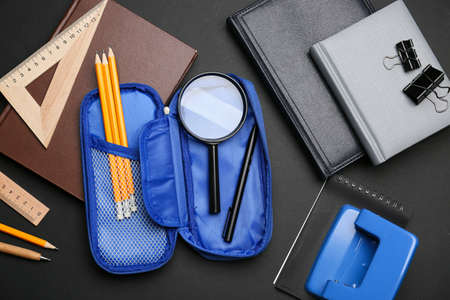 Pencil case with stationery on dark background
