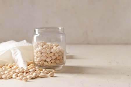 Jar with raw beans on light background