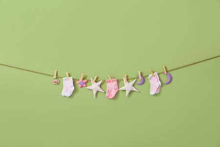 Baby socks, pacifier and toys hanging on rope against color backgroundの写真素材