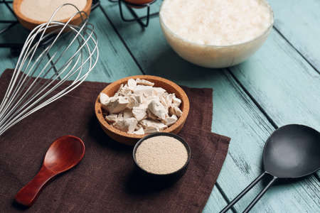Bowls with different yeast, whisk and spoons on color wooden backgroundの写真素材